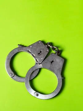 Handcuffs on the Green Background Stock Photos