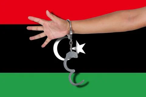 Handcuffs with hand on Libya flag Stock Photos
