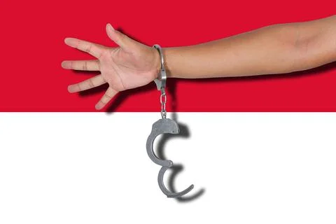 Handcuffs with hand on Monaco flag Stock Photos