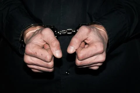 Handcuffs on hands of a arrested handcuffed criminal man Stock Photos