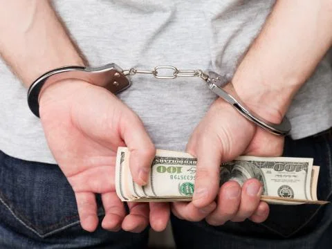 Handcuffs on hands holding money Stock Photos