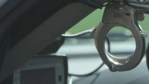 Handcuffs Hanging in a Car Window HD Video Stock Footage 89875803