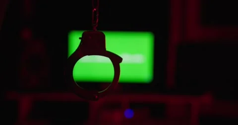 Handcuffs Hanging in Front of Green AI Screen Stock Footage 314031847