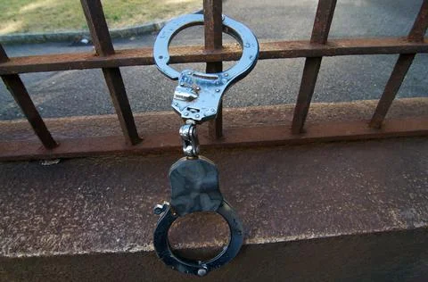Handcuffs hanging on a rusty railing Stock Photos