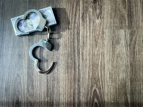 Handcuffs locked around a stack of hundred dollar bills Stock Photos