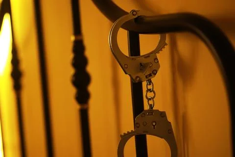Handcuffs Secured to Bed Frame in Dim Ambient Light Stock-Fotos