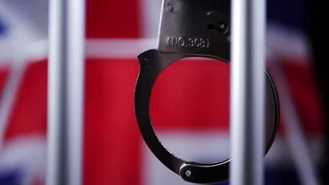 Handcuffs swing on prison bars with Union jack British flag background Stock Footage 171539653