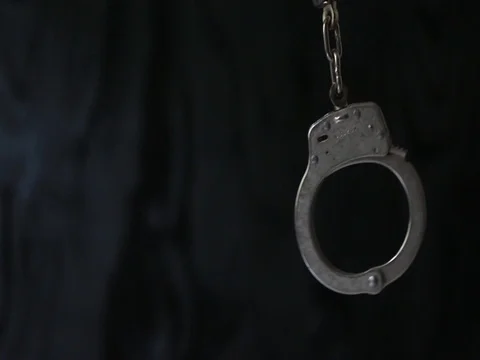 Handcuffs swinging on dark background Stock Footage 80071521