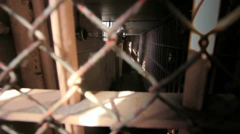 Handeld through grilled bars in old prison penetentiary detention area Stock Footage 10924822