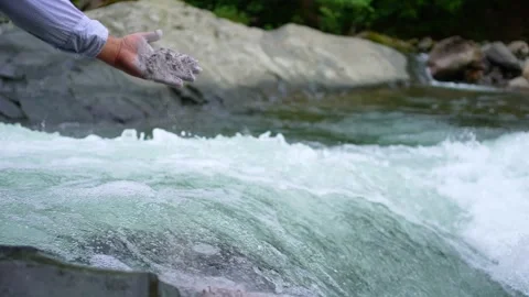 A handful of ashes after cremation in the hand scattering the ashes in the river Stock Footage 247136568
