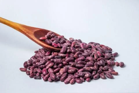 A handful of beans on a white background. On beans a wooden spoon. Stock Photos