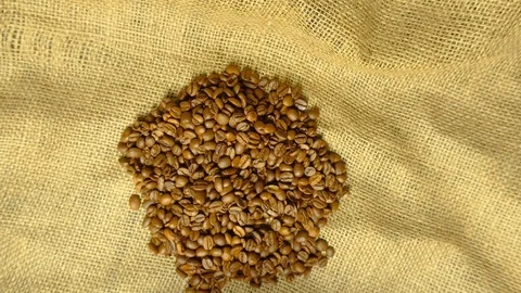 A handful of brown, roasted coffee beans on burlap sacking background, macro Stock Footage 103098974
