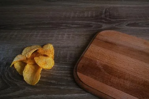 A handful of corrugated chips on a table next to a cutting board with free space Foto stock