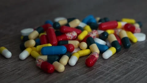 A handful of multi-colored pills lying on the table. 4k footage 스톡 동영상 194181967