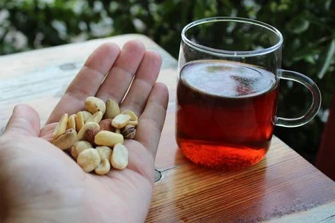 A handful of nuts and a mug of black Turkish tea. Stock Photos