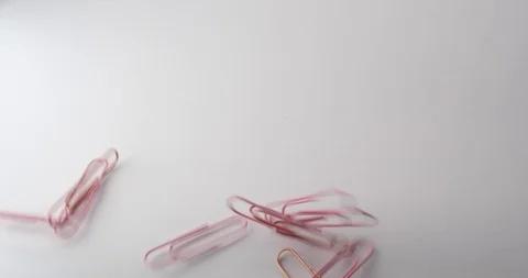 A handful of paperclips thrown onto a table in slow motion Stock Footage 117349456