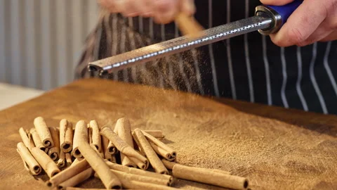 Handgrating cinnamon on wooden surface for brewing or baking Stock Footage 324788157