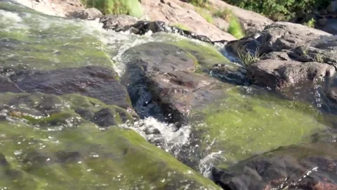 Handheald shot of a small waterfall or cascade on a sunny day from the top with  Stock Footage 104926146