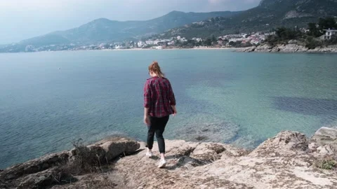 Handheld 4K shot of happy young woman walking on the rocks by the sea. Stock Footage 152004334