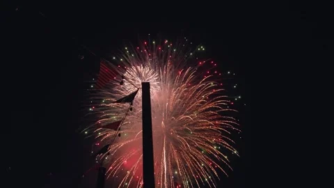 Handheld Active Fireworks with American Flags in Foreground - night time 스톡 동영상 347928291