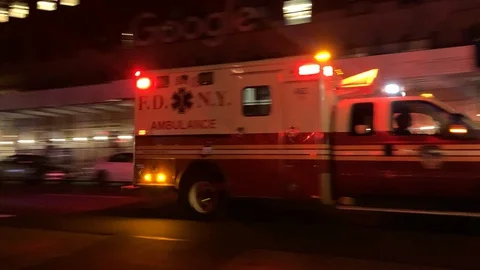 Handheld: Ambulance with lights rushing down empty NYC Street during COVID-19 Stock Footage