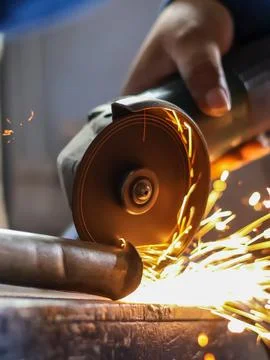 Handheld angle grinder cutting metal with sparks. Stock Photos