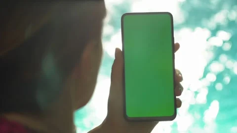 Handheld Camera: back view of brunette holding chroma key green screen Stock Footage 137684544
