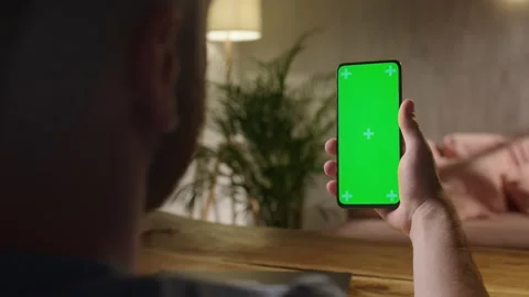 Handheld Camera: Back View of Man Holding Chroma Key Green Screen Smartphone Stock Footage 164921635