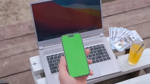 Handheld Camera: Man's hands use smartphone on with green screen with laptop, on Stock Footage 247228157