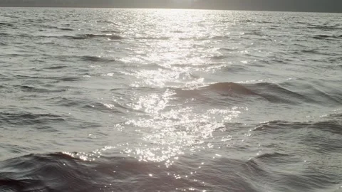 Handheld camera sliding above water surface with sun reflecting on waves slow Stock Footage 145180750