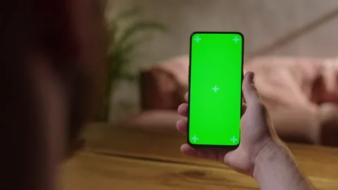 Handheld Camera: Young Man at Home Holding Chroma Key Green Screen Smartphone Stock Footage 164921621