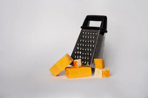 Handheld cheese grater with blocks of differernt dairy cheeses Stock Photos