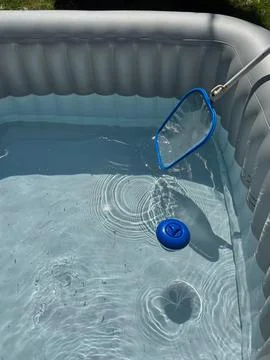 Handheld cleaning net and floating chemical dispenser in a hot tub. Stock Photos