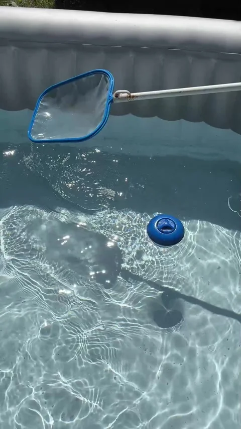 Handheld cleaning net used to clean an outdoor hot tub. Stock Footage 344997416