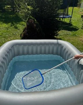 Handheld cleaning net used to clean an outdoor hot tub. Stock Photos