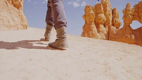 Handheld close-up of boots walking on desert trail Stock Footage 128837074