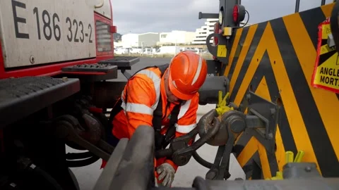 Handheld Close-up of Railway Worker Engaging Coupler Mechanism on Freight Train Stock Footage 337976530