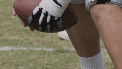 Handheld close up shot of center snapping football on field Stock Footage 120304222