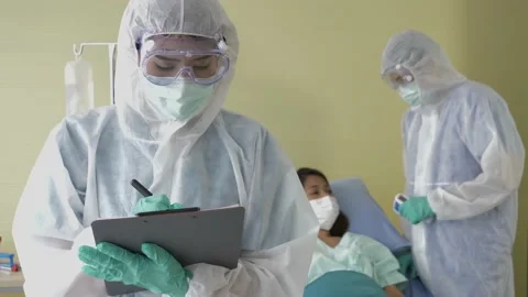 A handheld close-up shot of the doctors in a PPE suit with a female patient. Stock Footage 146692218