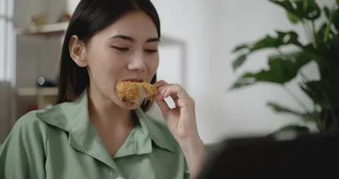 Handheld Close up shot, face of Asian young woman eating fried chicken Stock Footage 240396516
