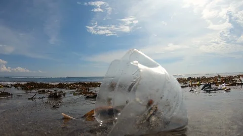 Handheld close up shot of garbage on polluted beach near sea on sunny day, Bali Stock Footage 140290169