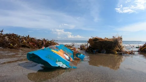 Handheld close up shot of garbage on polluted beach near sea on sunny day, Bali Stock Footage 140290426