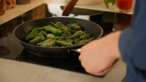 Handheld close-up shot of a man cooking pepper in frying pan on the stove Vídeo Stock 114846757