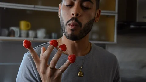 Handheld close-up shot of a man eating raspberries in the kitchen Stock-Footage 115059992