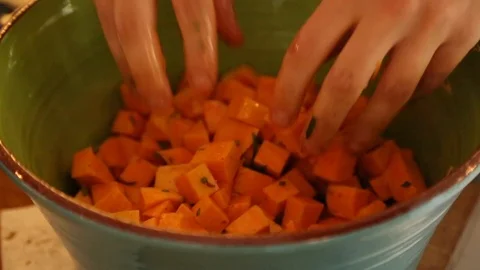 Handheld close-up shot of a man mixing diced carrots in a bowl Vídeo Stock 114846810