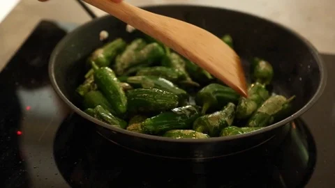 Handheld close-up shot of stirring roasted pepper in frying pan on the stove Vídeo Stock 114846751