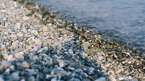 Handheld close-up of waves flowing over the pebbles on the sea coast Stock Footage 122398099