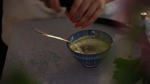 Handheld close-up of woman adding salt and pepper in cream in kitchen Stock Footage 114883388