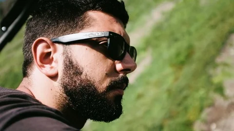 Handheld close-up of a young man with beard wearing sunglasses Stock Footage 122396560