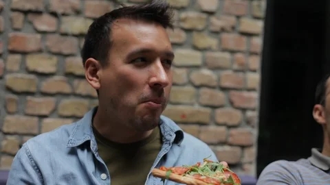 Handheld close-up of young man enjoys pizza outdoors in an urban setting Stock Footage 114848242